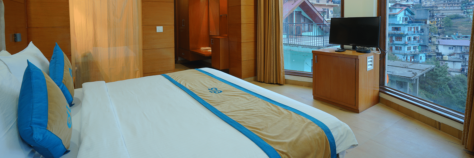 A bedroom  showcasing the view through glass windows and a TV on a table at DLS Hotels The Rock Castle.